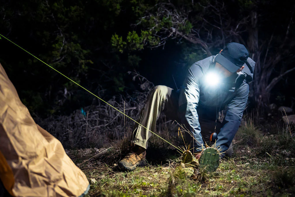 illumibite 2-in-1 flashlight being used with bite grip while setting up a tent at night, providing bright LED lighting for hands-free outdoor setup
