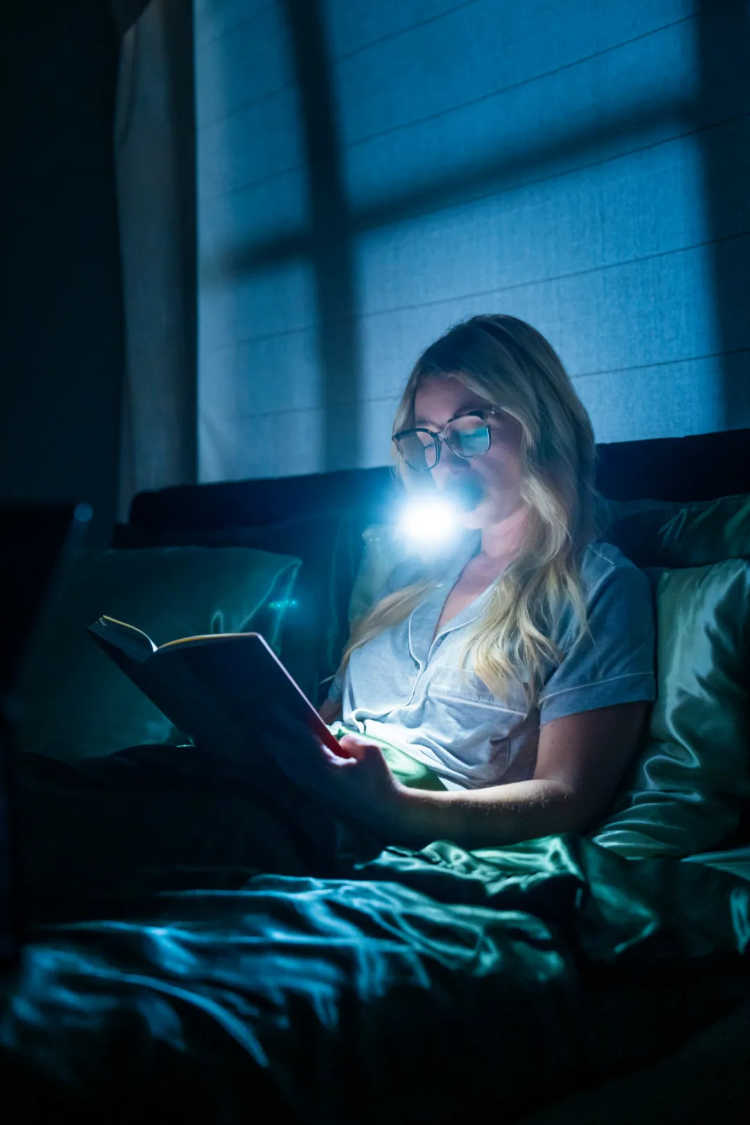 illumibite 2-in-1 flashlight being used in bed while reading, providing soft hands-free lighting for nighttime comfort and visibility without disturbing others